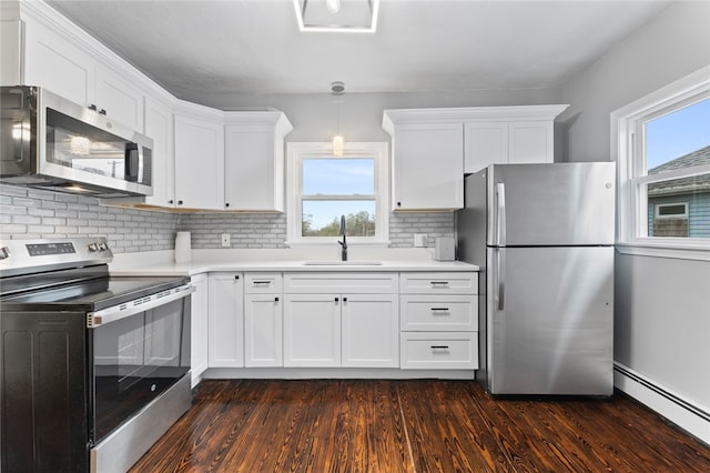 kitchen featuring light countertops, a sink, appliances with stainless steel finishes, and a baseboard radiator