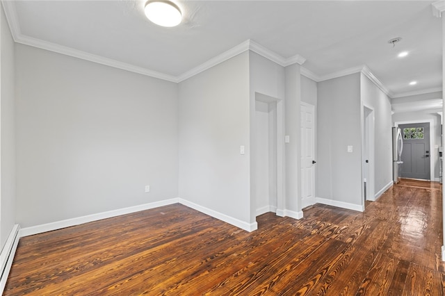 spare room with a baseboard heating unit, dark wood-style floors, ornamental molding, and baseboards
