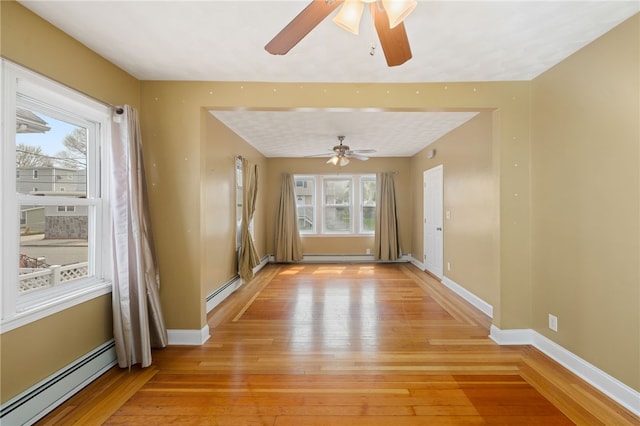 empty room featuring a baseboard radiator, a ceiling fan, and light wood-style flooring