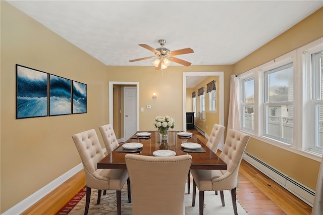 dining area featuring a baseboard radiator, a baseboard heating unit, light wood-style floors, baseboards, and a ceiling fan