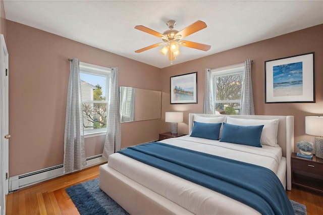 bedroom featuring wood finished floors, ceiling fan, and multiple windows