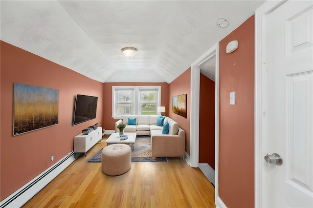 living area featuring baseboards, baseboard heating, lofted ceiling, and light wood-style floors