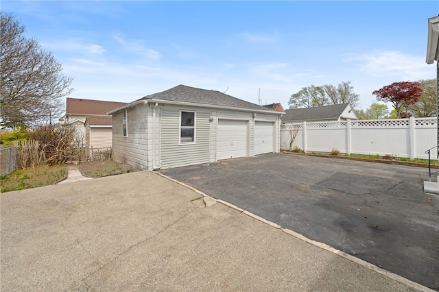 garage featuring driveway and fence