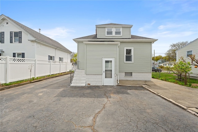rear view of property featuring fence, a patio area, and roof with shingles
