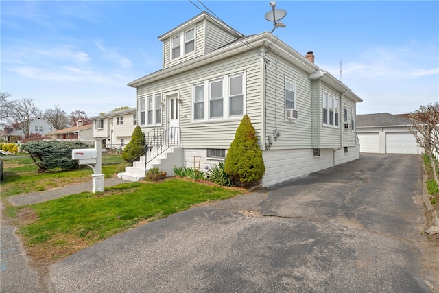 view of front of house featuring a front yard, an outbuilding, cooling unit, a detached garage, and a chimney