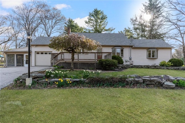 ranch-style home featuring a chimney, a wooden deck, driveway, a front lawn, and an attached garage