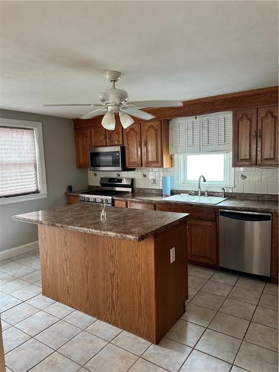 23 Pengrove St, Cranston, RI 02920 - kitchen featuring stainless steel appliances, a sink, light tile patterned floors, backsplash, and an island with sink