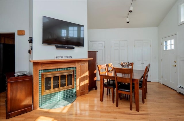 dining room featuring track lighting, wood finished floors, and a tile fireplace
