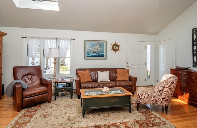 living area featuring lofted ceiling with skylight and wood finished floors