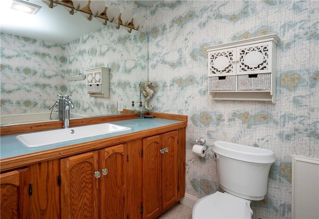 half bath with toilet, tile patterned floors, wallpapered walls, and vanity