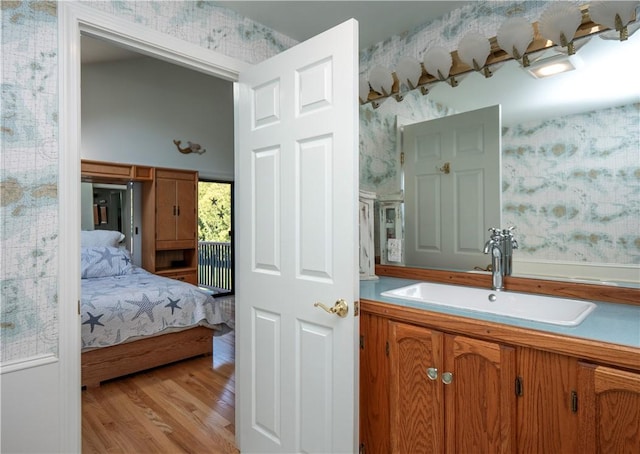 ensuite bathroom with vanity, wallpapered walls, wood finished floors, and ensuite bathroom