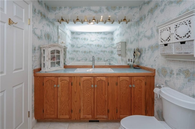 bathroom with wallpapered walls, toilet, tile patterned flooring, and a sink