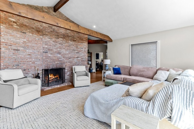 living area featuring brick wall, vaulted ceiling with beams, a brick fireplace, and wood finished floors