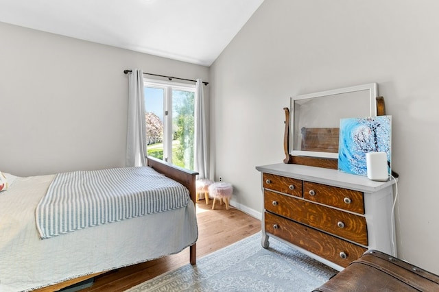 bedroom with baseboards, wood finished floors, and vaulted ceiling
