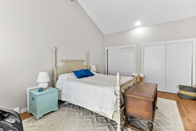 bedroom with multiple closets, lofted ceiling, and wood finished floors