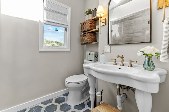 bathroom featuring baseboards, tile patterned floors, and toilet