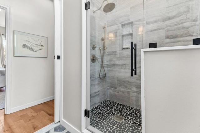 bathroom featuring baseboards, wood finished floors, and a tile shower