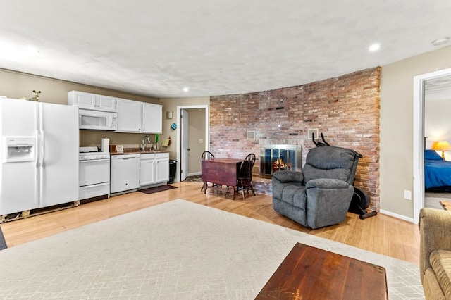living area with recessed lighting, light wood-style flooring, a brick fireplace, and baseboards
