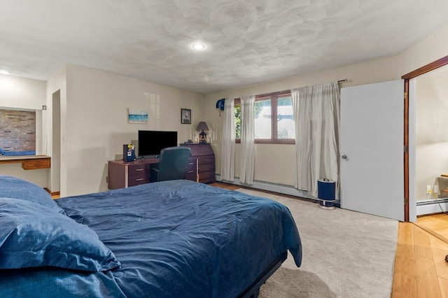 bedroom featuring a baseboard heating unit, recessed lighting, and wood finished floors
