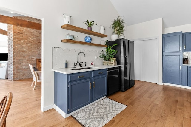 kitchen with light wood-type flooring, light countertops, blue cabinets, a sink, and black appliances