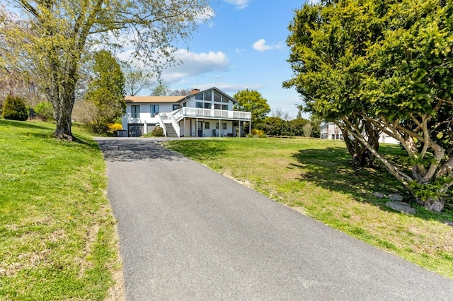 view of front of home featuring driveway, stairs, and a front yard