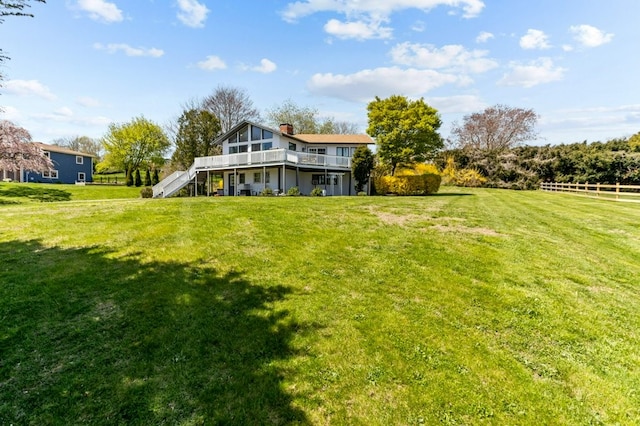rear view of house with a lawn, a wooden deck, a chimney, and stairway