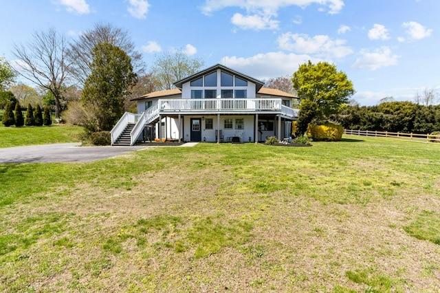 back of house with fence, a lawn, a deck, and stairway