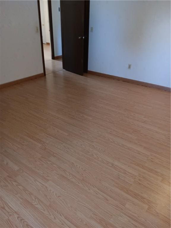 empty room with baseboards and light wood-style flooring