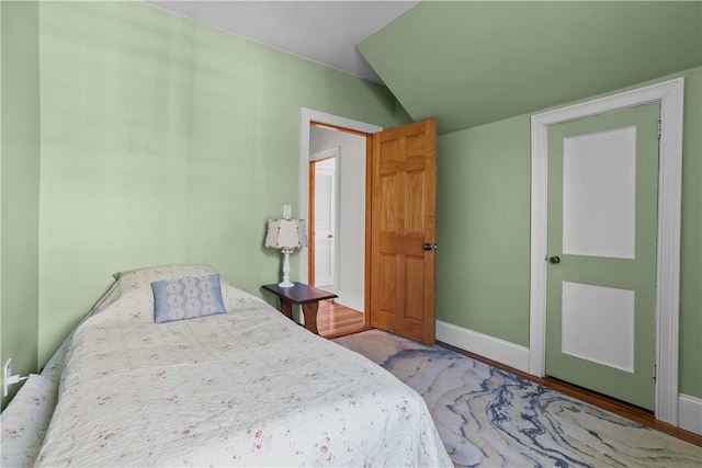 bedroom featuring baseboards and lofted ceiling
