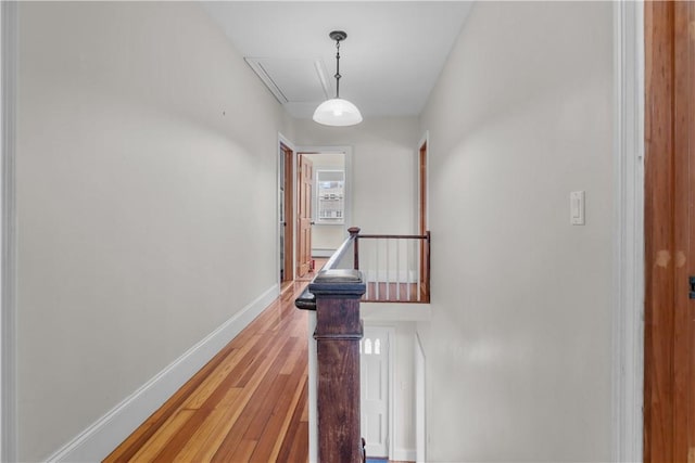 corridor featuring attic access, an upstairs landing, baseboards, and light wood-type flooring