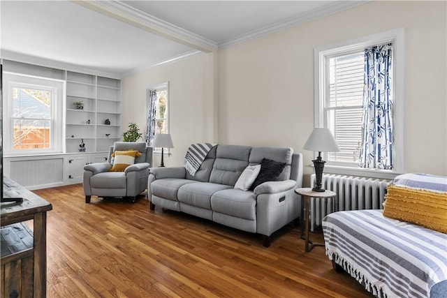 living area with radiator, crown molding, hardwood / wood-style flooring, and plenty of natural light