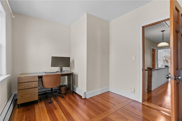 office area with baseboard heating, baseboards, and hardwood / wood-style floors