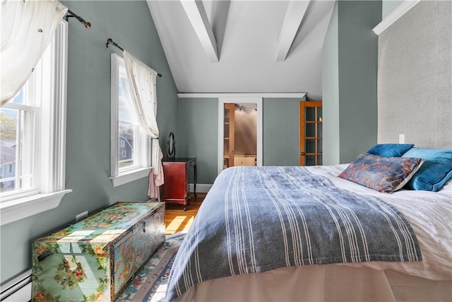 bedroom featuring lofted ceiling, wood finished floors, and a baseboard heating unit