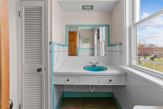 bathroom with tile walls, vanity, a wainscoted wall, and a closet