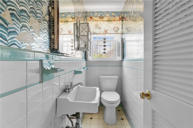 half bath with wallpapered walls, toilet, tile patterned flooring, and a sink