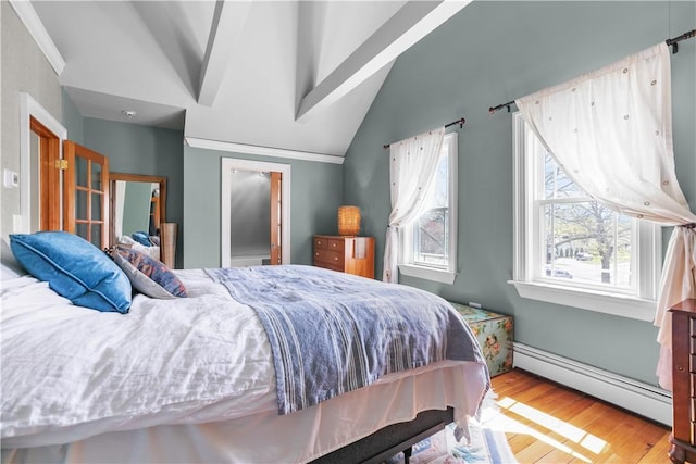 bedroom featuring lofted ceiling, wood finished floors, and a baseboard heating unit