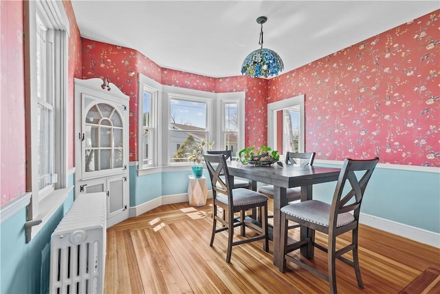 dining area featuring radiator, baseboards, wallpapered walls, and light wood-style floors