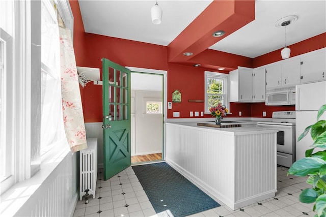 kitchen featuring radiator, white appliances, wainscoting, light countertops, and white cabinets