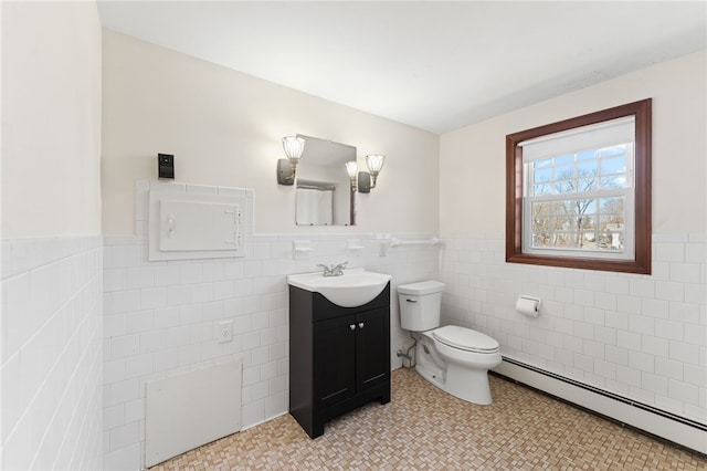 bathroom with tile walls, a wainscoted wall, a baseboard heating unit, and toilet