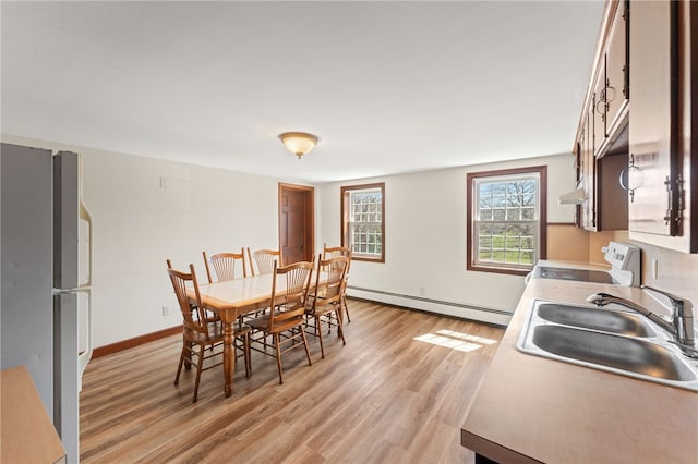 dining space with baseboard heating, baseboards, and light wood-style floors
