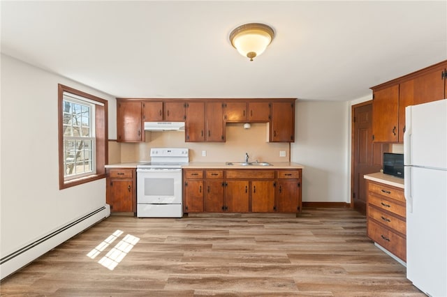 kitchen with a baseboard heating unit, a sink, under cabinet range hood, white appliances, and light countertops