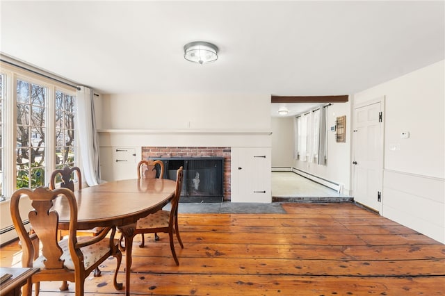 dining room featuring a fireplace, hardwood / wood-style floors, and baseboard heating