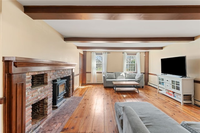 living area featuring beam ceiling, a brick fireplace, light wood-style flooring, baseboards, and baseboard heating