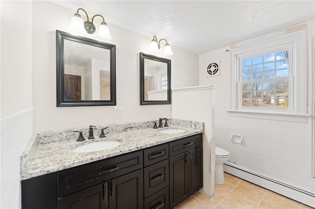 full bathroom featuring a baseboard radiator, tile walls, tile patterned flooring, and a sink