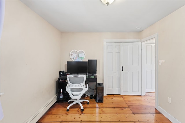 office area with baseboards, light wood-style flooring, and a baseboard radiator