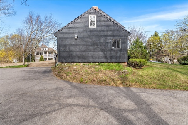 view of property exterior with a yard and aphalt driveway