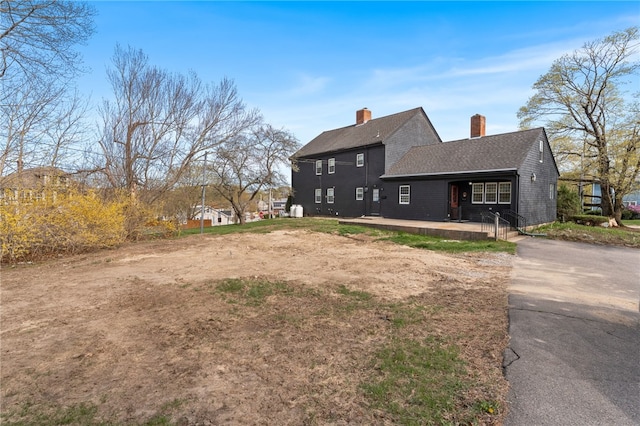 view of property exterior featuring a chimney and a shingled roof