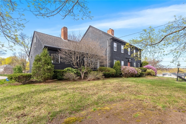 view of property exterior featuring a lawn, roof with shingles, and a chimney