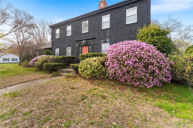 colonial home with a chimney and a front yard