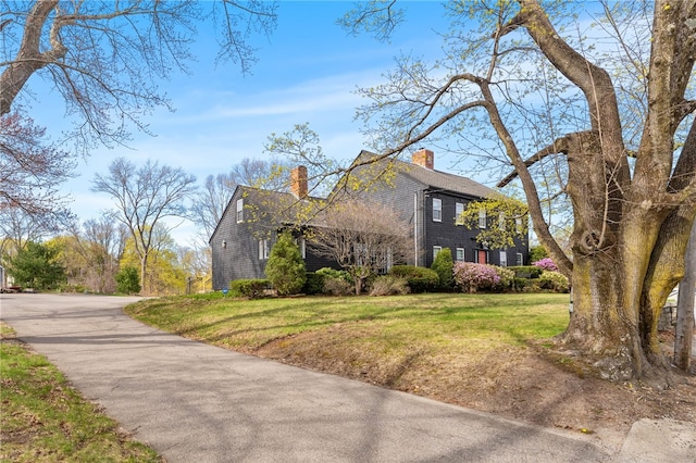 view of side of home with a yard and a chimney